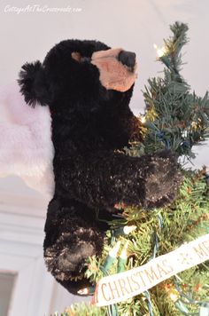 a black teddy bear sitting on top of a christmas tree