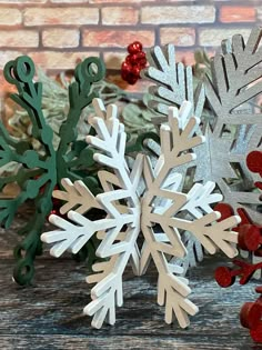 two snowflakes sitting next to each other on top of a wooden table with red and green decorations