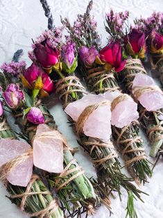 flowers tied together with twine and pink stones on a white tableclothed surface