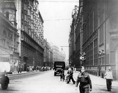 an old black and white photo of people walking down the street