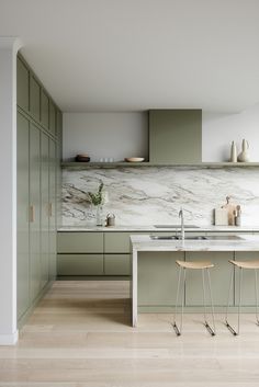 a kitchen with green cabinets and marble counter tops