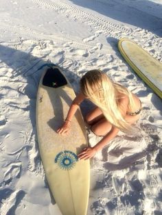 a woman laying on top of a surfboard in the snow