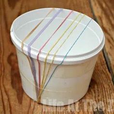 a white plastic container with multicolored stripes on the lid sitting on a wooden table