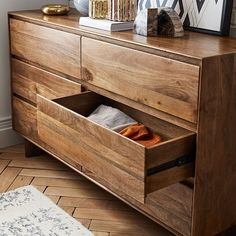 a wooden dresser with two open drawers and a framed photograph on the wall above it