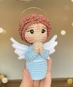 a small crocheted angel doll is held up to the camera