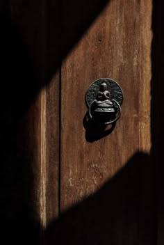 a door handle on a wooden door with the shadow of a person's head