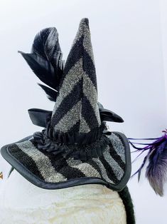 This Witch Hat Fascinator is an easy and classy way to dress up this year! This is a black and silver witch hat that is attached to a black yarn wrapped headband. The hat is adorned with ruffled lace, a netted flower, rhinestones and iridescent feathers. Will Fit a 4 year old and up! Like our Facebook Page and get 10% off when you message me before checkout! Everything made by handmade MKE is one of a kind and unique, however, if you would like a different size or see a piece that you would like Themed Fitted Costume Hats And Headpieces, Novelty Brimmed Halloween Costume Hats And Headpieces, Novelty Brimmed Halloween Costume Hat, Curved Brim Costume Hats And Headpieces, Novelty Brimmed Costume Accessories For Costume Party, Novelty Brimmed Costume Accessories For Party, Curved Brim Costume Hat, Costume Hat With Curved Brim, Fitted Mini Hats For Themed Events