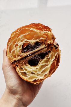 a person holding up a pastry that has been cut in half to show it's filling