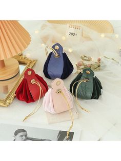 four different colored purses sitting on top of a white table next to a lamp