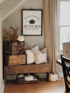 a wooden crate filled with pumpkins sitting on top of a table next to a window