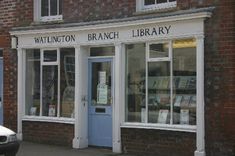 a car parked in front of a branch library on the side of a street next to a brick building