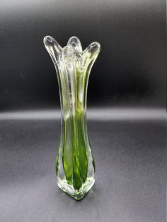 a green glass vase sitting on top of a gray tablecloth covered flooring with a black background