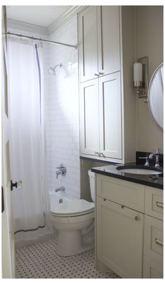 a white toilet sitting next to a sink in a bathroom under a mirror and shower curtain