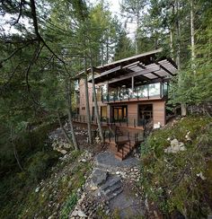 a small cabin in the woods with stairs leading up to it's second floor