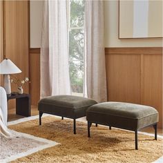 a living room with two footstools and a rug in front of the window