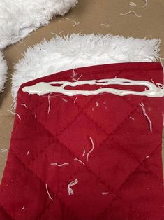 a white teddy bear laying on top of a red blanket next to a pile of fur