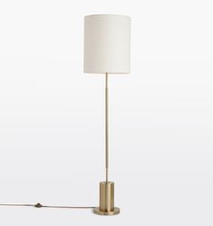 a floor lamp with a white shade on the base and a gold colored metal frame