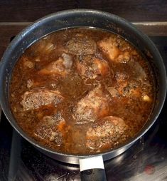 a pot filled with meat sitting on top of a stove