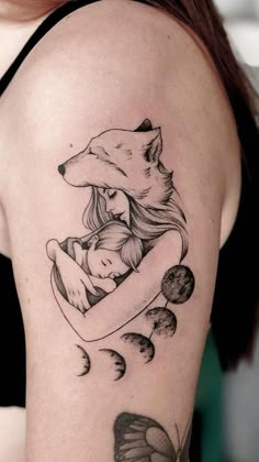 a woman with a tattoo on her arm holding a bear and moon in the shape of a heart