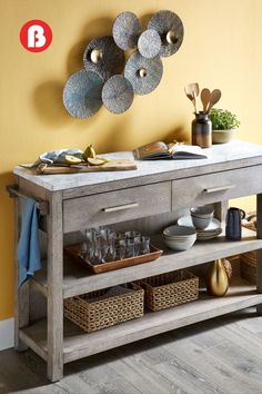 a wooden table with plates and glasses on it next to a wall mounted art piece