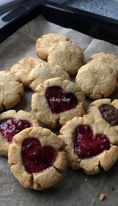 cookies with jam in the middle are on a baking sheet and ready to be eaten