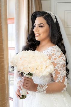 a woman in a wedding dress holding a bouquet of flowers and smiling at the camera