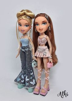 two dolls are standing next to each other on a white background, one is holding a purse