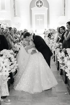 a bride and groom kiss as they walk down the aisle