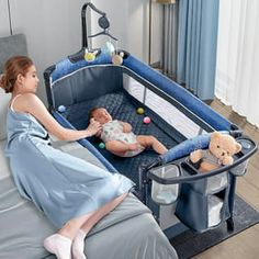 a woman laying on top of a bed next to a baby in a crib