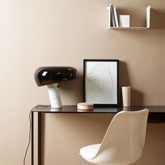 a white chair sitting next to a desk with a lamp on it