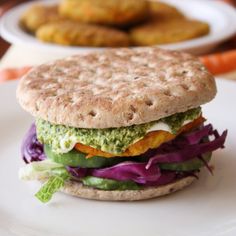 a close up of a sandwich on a plate with carrots and pickles in the background