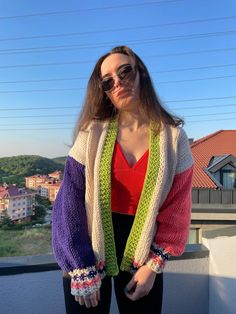 a woman standing on top of a roof with her hands in her pockets and wearing sunglasses