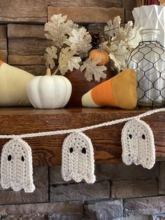 a crocheted ghost garland on a mantle with pumpkins and other fall decorations