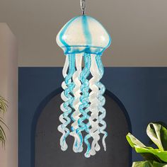 a blue and white jellyfish light hanging from a ceiling in a room with potted plants