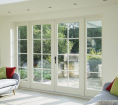 a living room filled with white furniture and lots of glass doors leading to an outside patio