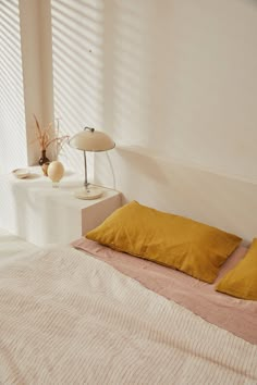 a bed with two pillows on top of it next to a lamp and other items