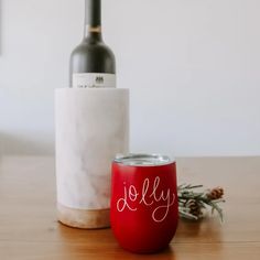 a red wine glass sitting on top of a wooden table next to a bottle of wine