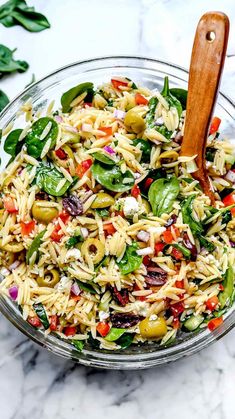 a bowl filled with pasta salad on top of a marble counter