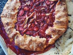 a strawberry pie sitting on top of a piece of parchment paper covered in jelly sauce