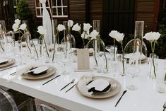 the table is set with white flowers and place settings for dinner guests to sit at