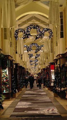 an empty shopping mall with christmas decorations on the ceiling and people walking down the aisle