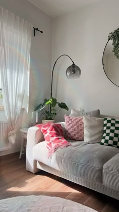 a living room filled with furniture and a large mirror on the wall above it's windows