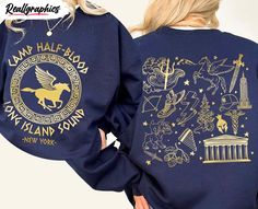 the back of a woman's blue sweatshirt with gold foiling on it, featuring images of buildings and symbols