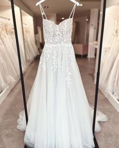 a white wedding dress hanging on a rack in a bridal gown shop with other dresses