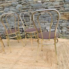 three chairs sitting next to each other in front of a stone wall