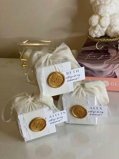 three small white bags with gold coins in them next to a teddy bear and some books