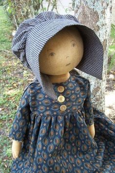 the doll is wearing a blue dress and hat with buttons on it's head