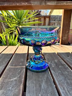 a blue glass bowl sitting on top of a wooden table next to a potted plant