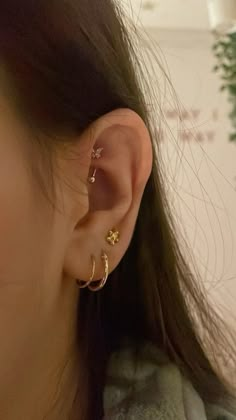 a close up of a person with ear piercings on their ears and behind them is a plant