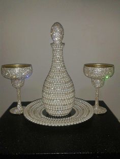 a table topped with three crystal goblets next to a bowl and candle holder